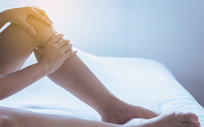 Woman's hand holding her leg below the knee