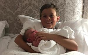 Smiling young boy holds a new born baby