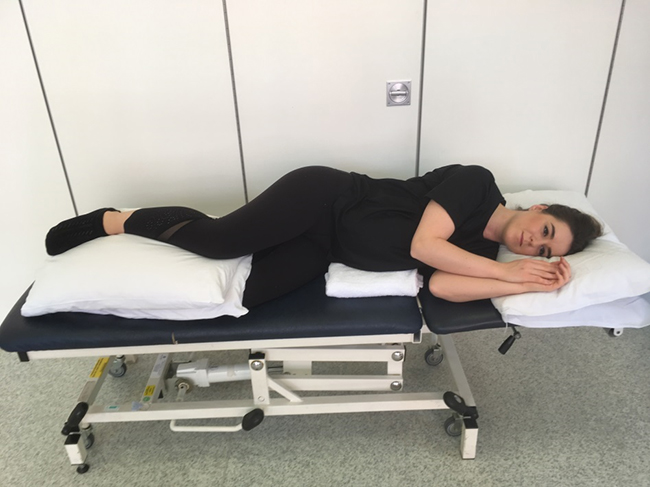 Woman lying on her side with a pillow between her bend legs