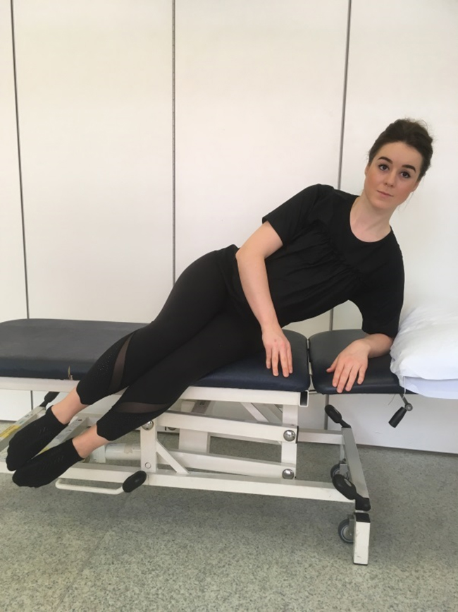 Woman semi-reclining on one elbow with her knees and ankles bent demonstrating how to get in and out of bed