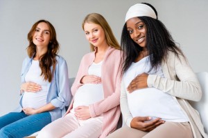 Three multicultural pregnant ladies holding their bumps