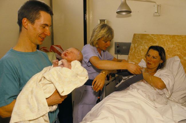 A mother reaches for her baby moments after she has given birth